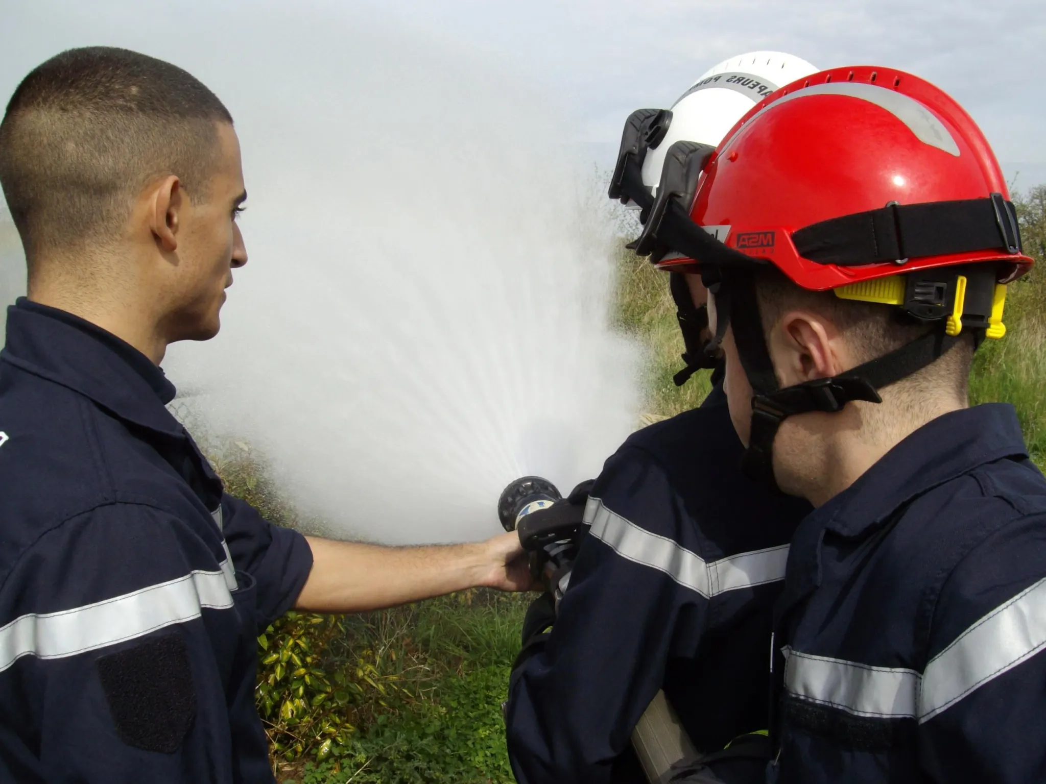 Trois formateurs utilisant un jet d'eau pour l'incendie