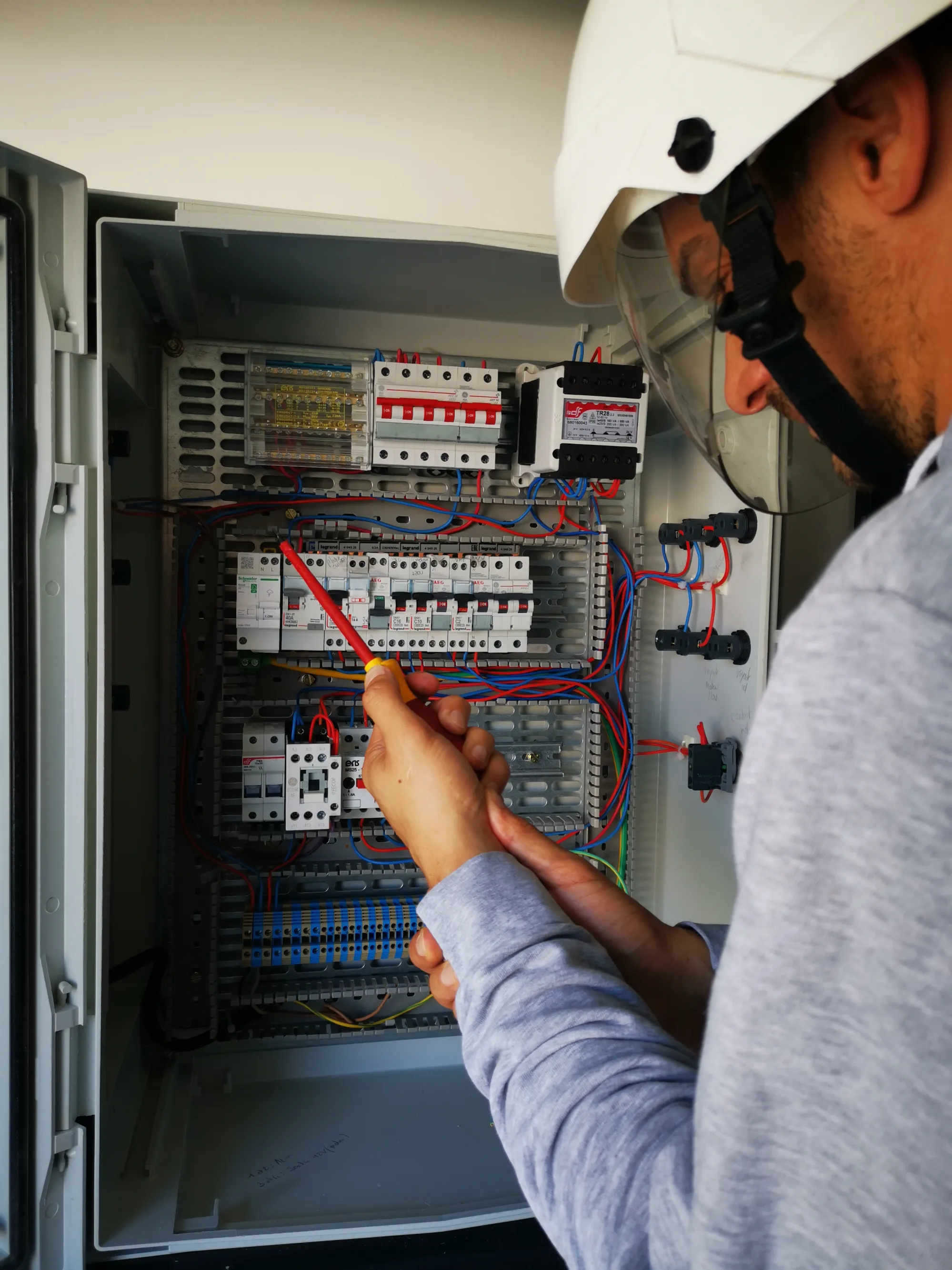 Technicien vérifiant un tableau électrique avec un outil